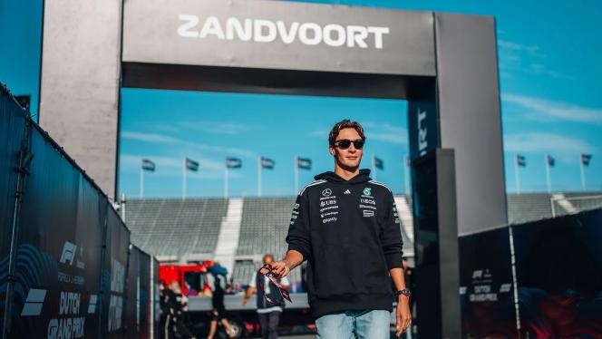 George Russell enters the race track grounds and walks through a large archway bearing the inscription ‘Zandvoort’.
