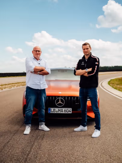 Maro Engel steht gemeinsam mit Produktmanager Jörg vor dem neuen Mercedes-AMG GT 63 S E Performance 4-Door