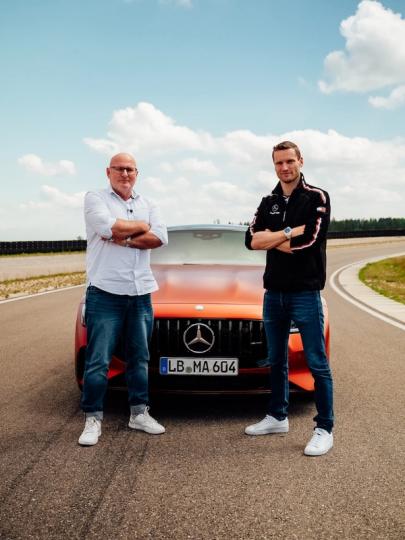 Maro Engel steht gemeinsam mit Produktmanager Jörg vor dem neuen Mercedes-AMG GT 63 S E Performance 4-Door