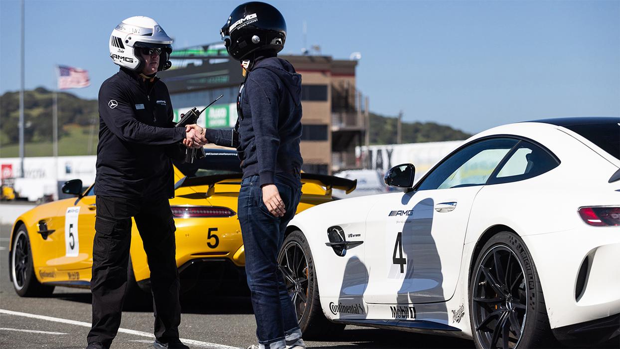 Two people who look like racing drivers shake hands