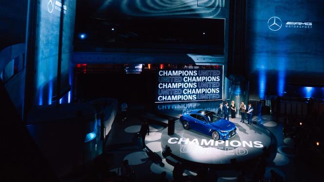 From a distance: Blue Mercedes-AMG GT and 6 people standing on a stage