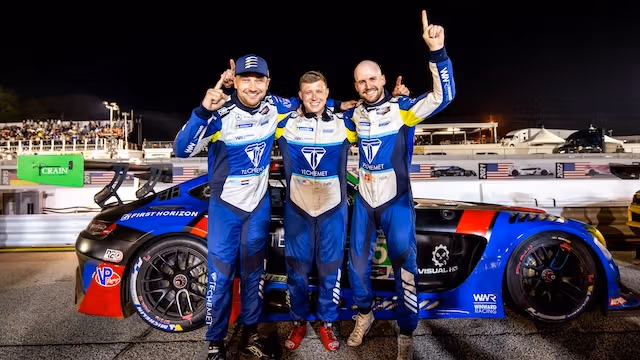 Three racing drivers stand in front of their Mercedes-AMG GT