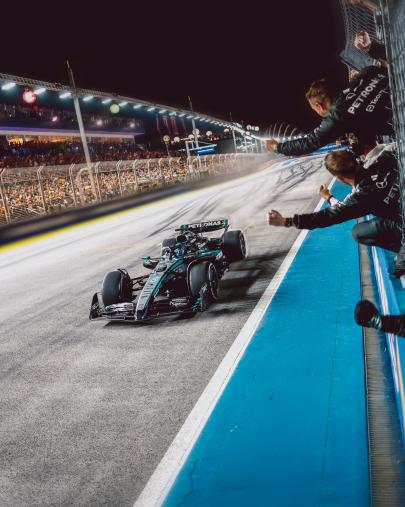 Das Team jubelt George Russell in seinem W16 zu, während er die Ziellinie überquert.