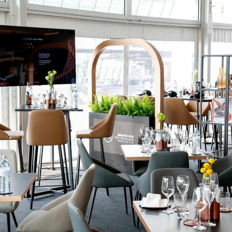 In der Club Suite stehen verschiedene, eingedeckte Tische mit dem Branding des Mercedes-AMG PETRONAS F1 Teams.