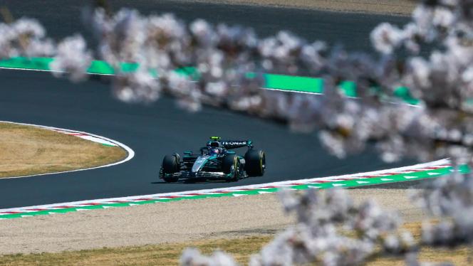 George Russel steht mit erhobenen Armen und einem speziell für das Rennen designten Helm an der Rennstrecke in Shanghai.