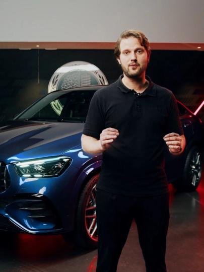 Produktmanager steht in einem Showroom vor dem neuen Mercedes-AMG GLE 53 Coupé
