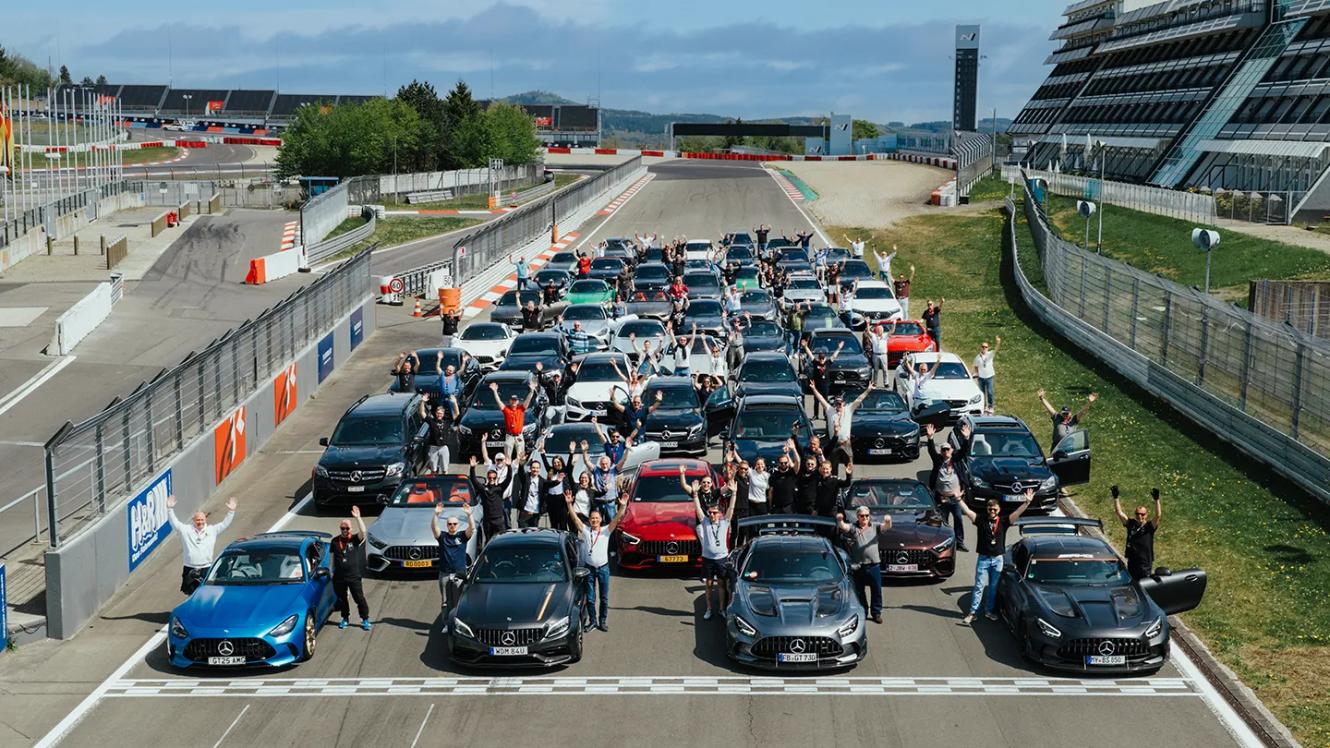 Mehrere Mercedes-AMG-Fahrzeuge und deren Besitzer auf der Rennstrecke beim Posieren für ein Gruppenfoto.