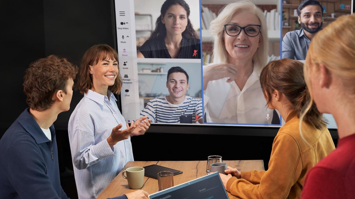 Eine Frau steht mit mehreren Menschen an einem Tisch.